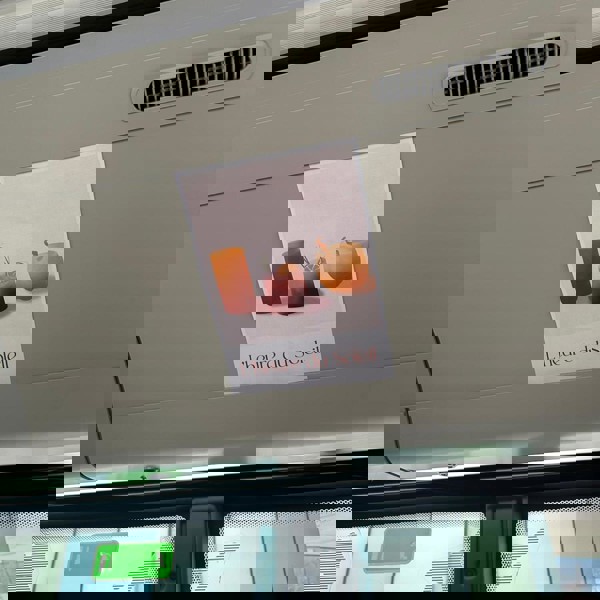 Een roze poster met zomerse cocktails en de tekst 'L'heure de soleil' hangt in een bus boven de toegangsdeuren. Een roze poster met zomerse cocktails en de tekst 'L'heure de soleil' hangt in een bus boven de toegangsdeuren.