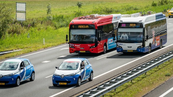 Twee Arriva-bussen rijden op de snelweg. Voor de bussen rijden toe blauw-witte Arriva auto's.
