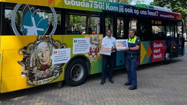Een meerkleurige Arriva-bus met de tekst 'Gouda 750! Kom jij ook op ons feest?'. Voor de bus staan een politieagent en een Arriva-medewerker die taart vasthouden.