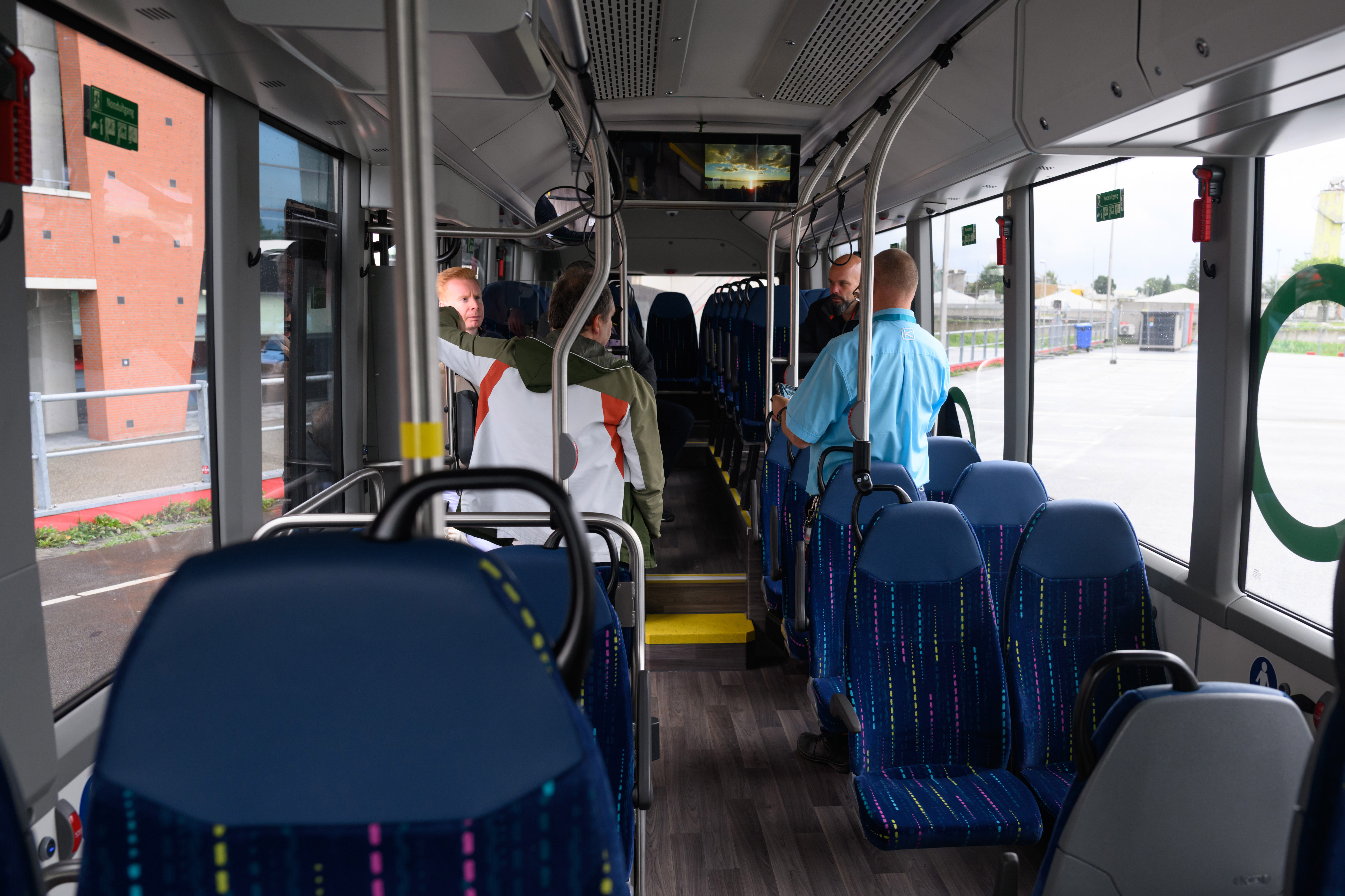 Vier reizigers in een bus staan klaar bij de uitgang om uit te stappen.