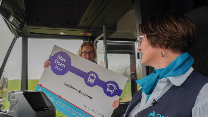 Wethouder van gemeente De Fryske Marren laat een vergrootte Meedoen Pas zien aan een chauffeur van Arriva in de bus