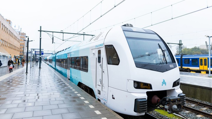 Een blauwe trein staat aan het verregende perron van station Groningen. Een blauwe trein staat aan het verregende perron van station Groningen.