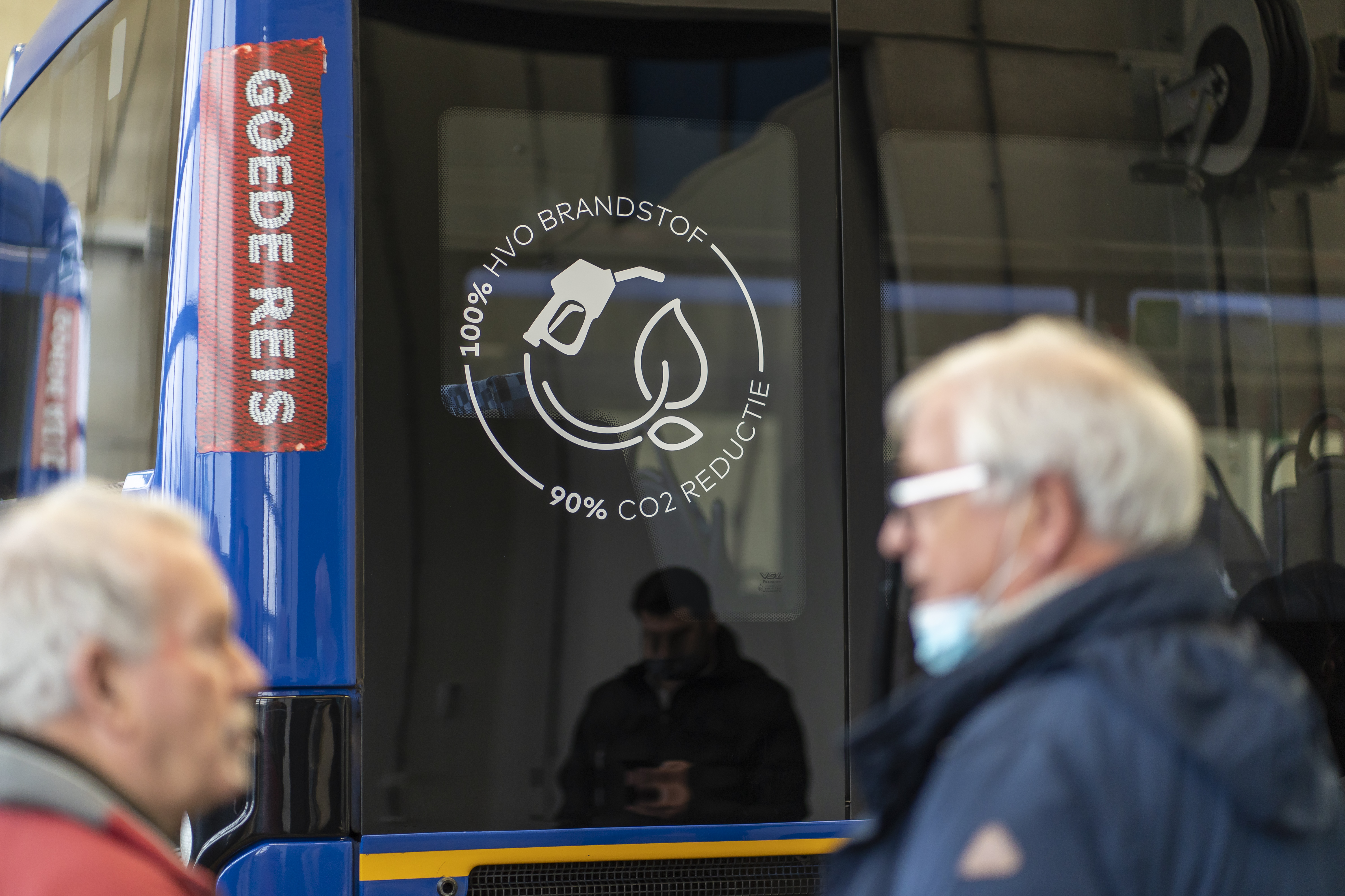 Twee mannen praten met elkaar terwijl ze voor een bus staan waarop het logo van HVO gebruik te zien is waarmee een CO2 reductie van 90% wordt gerealiseerd door Arriva