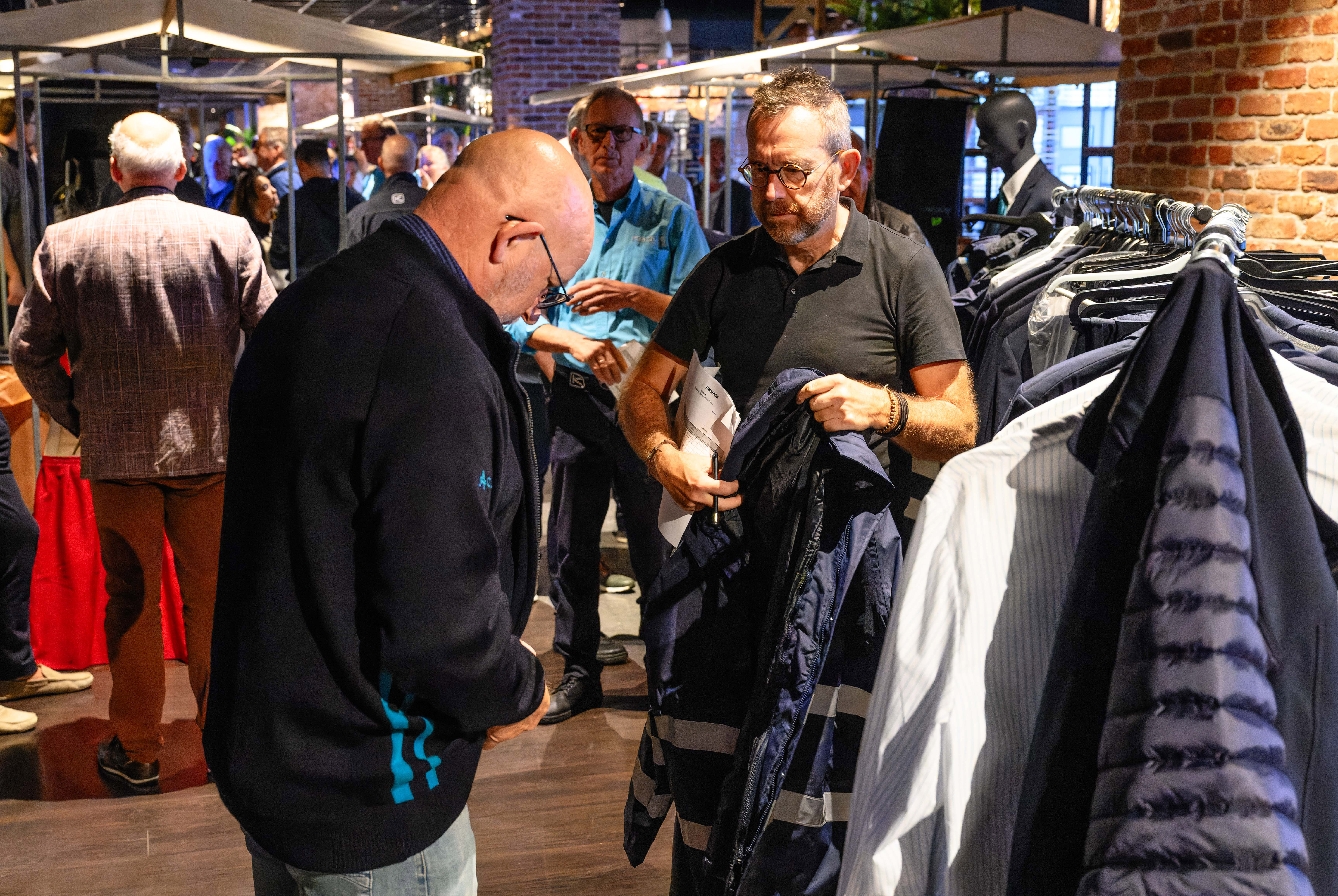 Een binnenruimte ingericht met stands en rekken kleding waar collega's van Arriva uniforms passen.