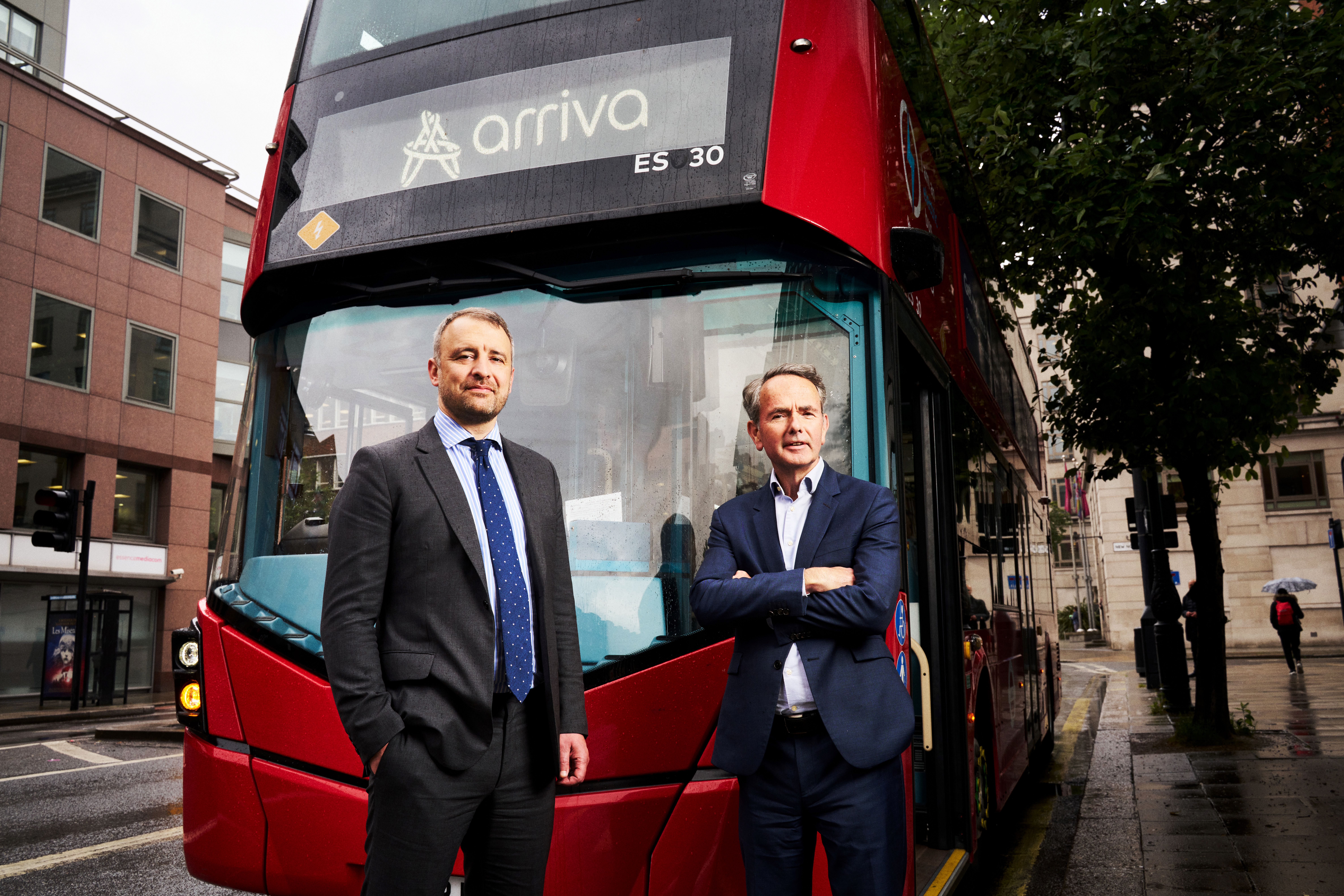 Voor een rode London bus van Arriva staan twee heren die I Squared en Arriva Group vertegenwoorden