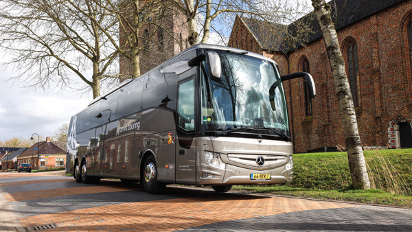 Bus Arriva Touring Grijze touringcar voor een kerk in een dorp