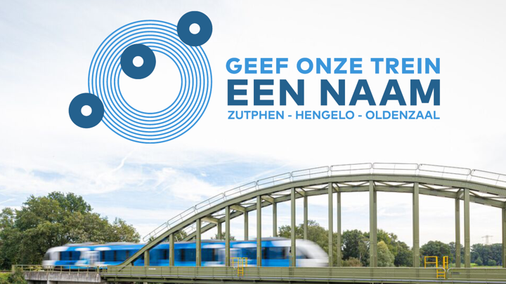 Een blauw-witte Arriva-trein rijdt over een spoorbrug met daarboven de tekst 'Geef onze trein een naam!'