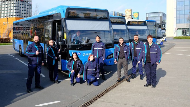 Achter servicemedewerkers poseren in uniform voor zes blauwe Arriva-bussen. Achter servicemedewerkers poseren in uniform voor zes blauwe Arriva-bussen.