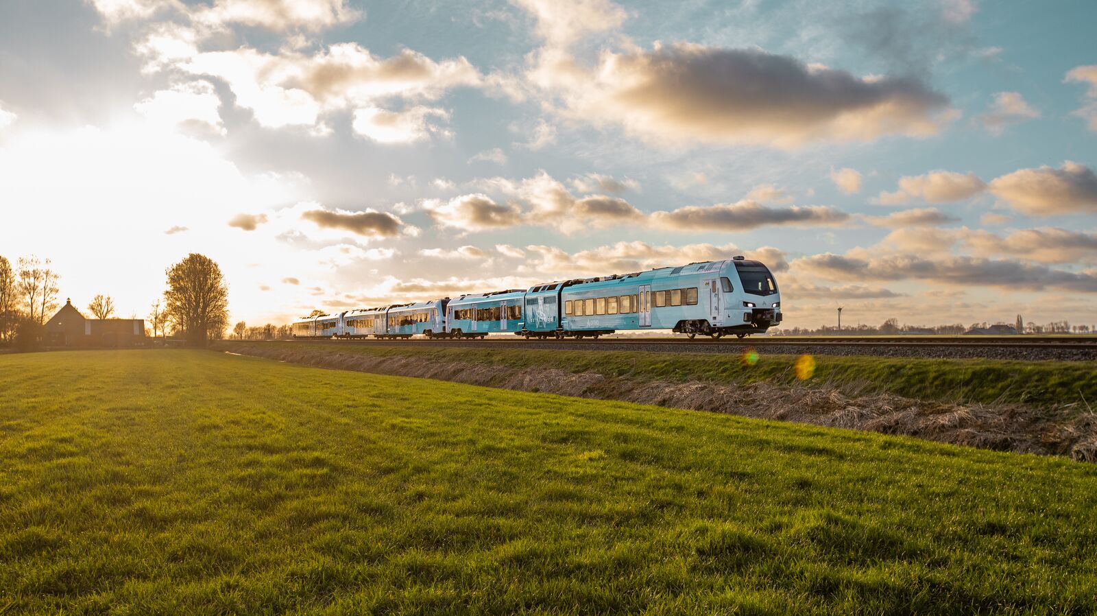 Arriva blauwe trein rijdt door zonning landschap.