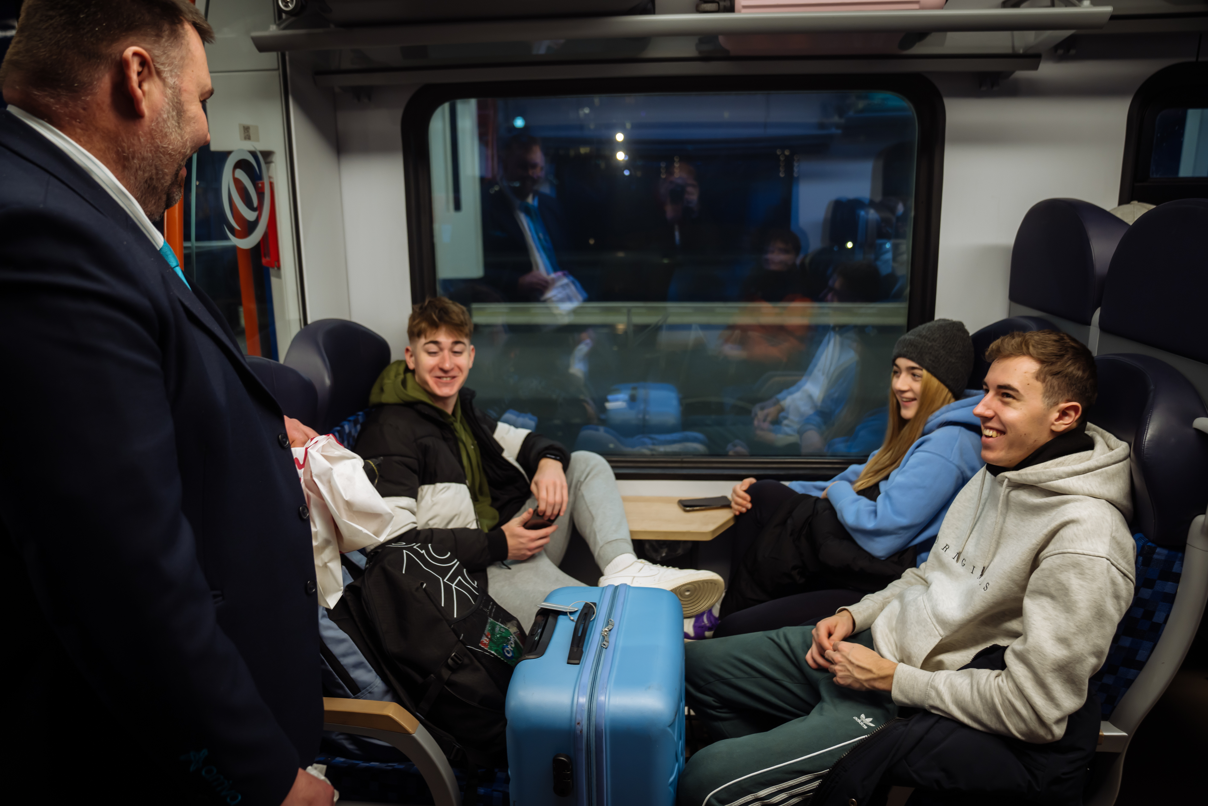 Blije reizigers in nachttrein Arriva met koffers en steward erbij  