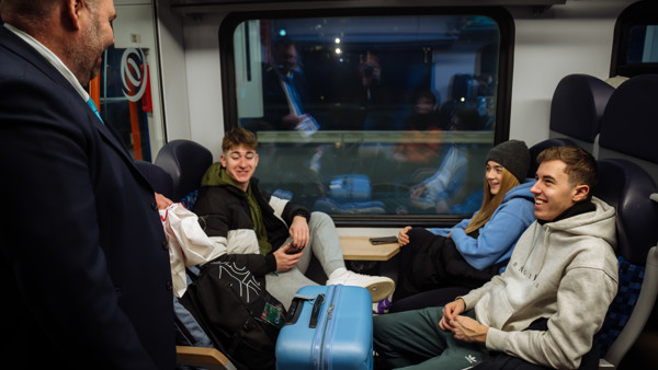 Blije reizigers in nachttrein Arriva met koffers en steward erbij Blije reizigers in nachttrein Arriva met koffers en steward erbij