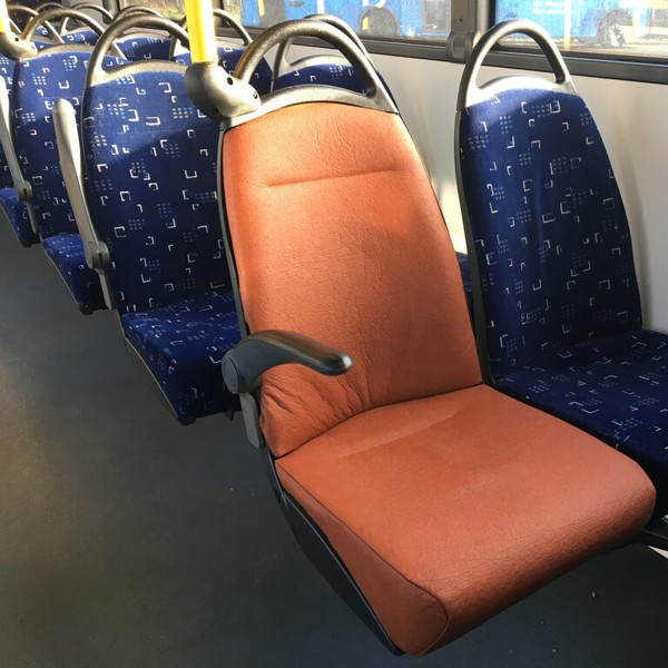 Een stoel in een bus in Friesland met bekleding van oranje fruitleer.