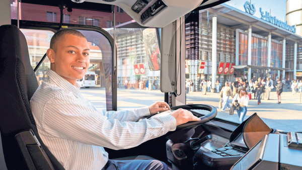 Studentchauffeur Tyrese glimlachend achter het stuur van de bus Studentchauffeur Tyrese glimlachend achter het stuur van de bus
