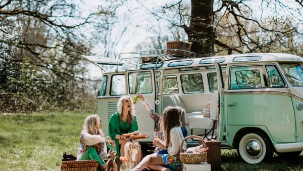 Gezellig stel zit voor een camper in de natuur te picknicken Gezellig stel zit voor een camper in de natuur te picknicken