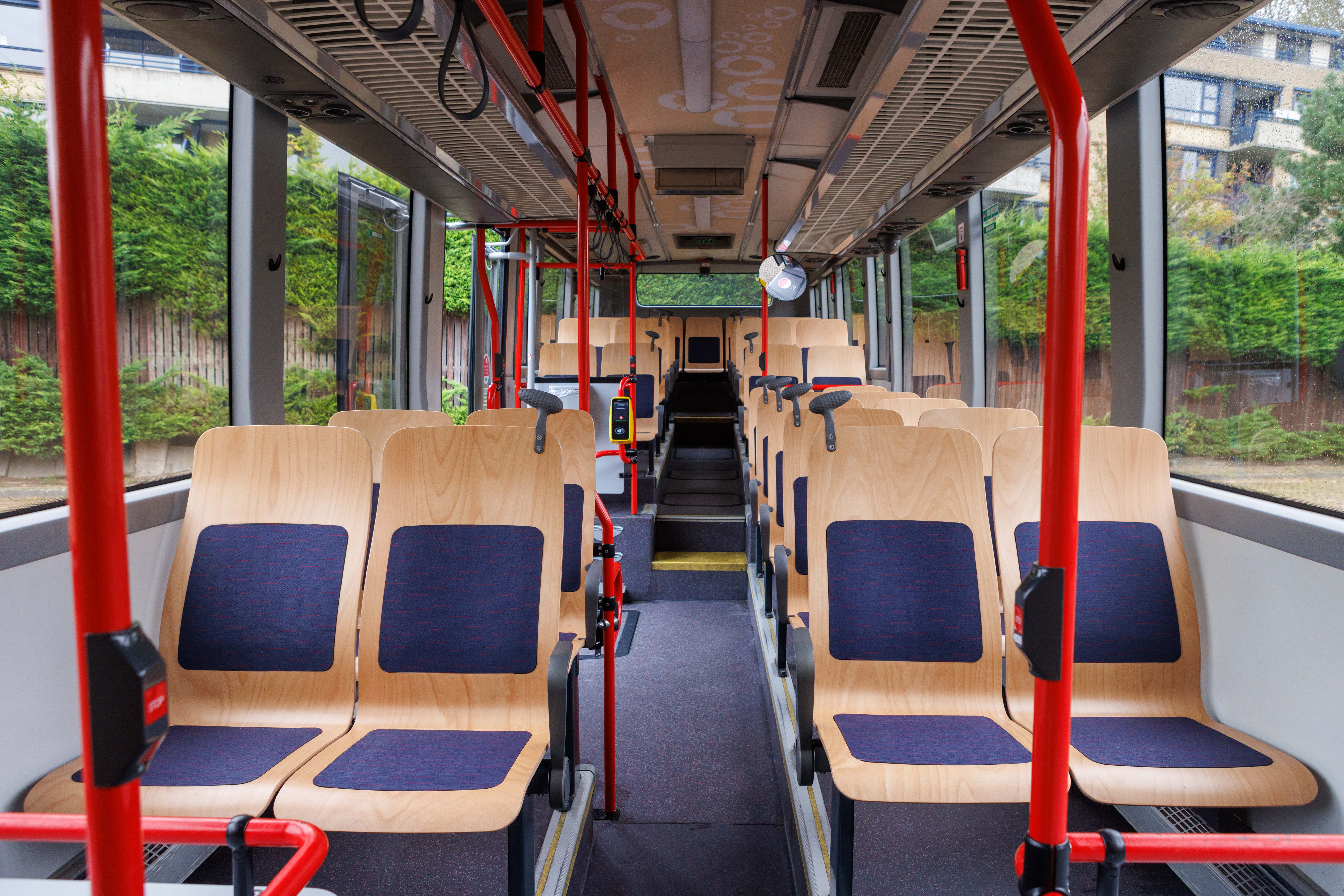 Lege bus met daarin hele rijen nieuwe blankhouten busstoelen, op circulaire en duurzame wijze gemaakt, met daarop in de midden een baan blauwe stof