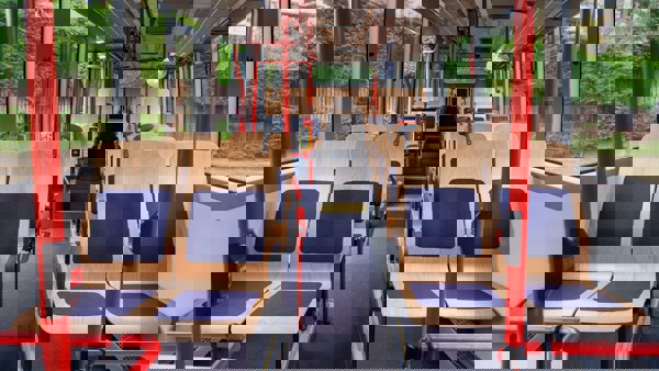 blankhouten circulair en duurzaam ontworpen busstoelen Lege bus met daarin hele rijen nieuwe blankhouten busstoelen, op circulaire en duurzame wijze gemaakt, met daarop in de midden een baan blauwe stof