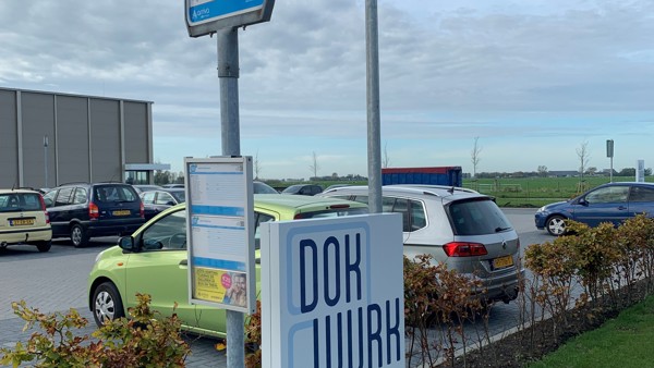 Een parkeerplaats met een bushaltebord en een bord met de tekst 'Dokwerk, p-personeel'.