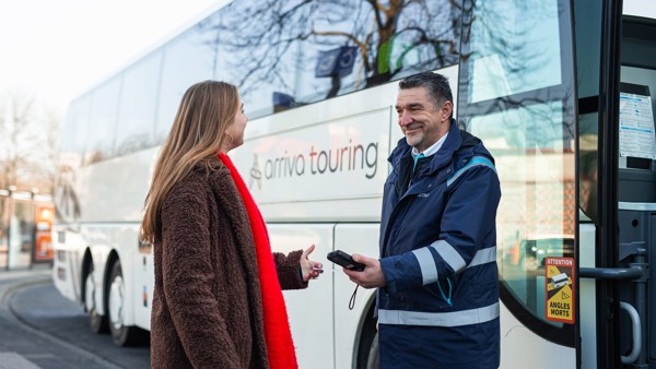 Steward controleert mevrouw op treinvervangend vervoer ticket man bij bus checkt ticket bij treinvervangend vervoer voor de buitendienststelling van Arriva