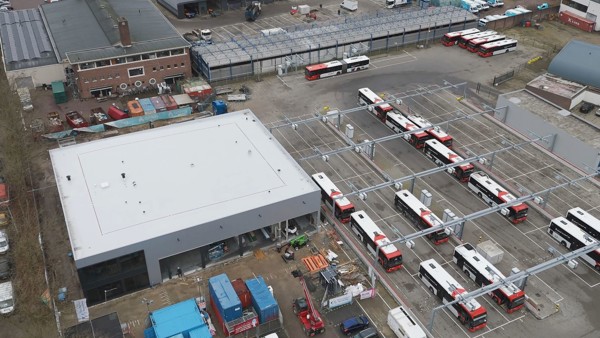 Bovenaanzicht nieuwe werkplaats en stalling van Arriva in Tilburg. Bovenaanzicht van een vierkant gebouw (werkplaats Tilburg) met rechts daarvan een stuk of 10 bravo bussen bij laadinfra.