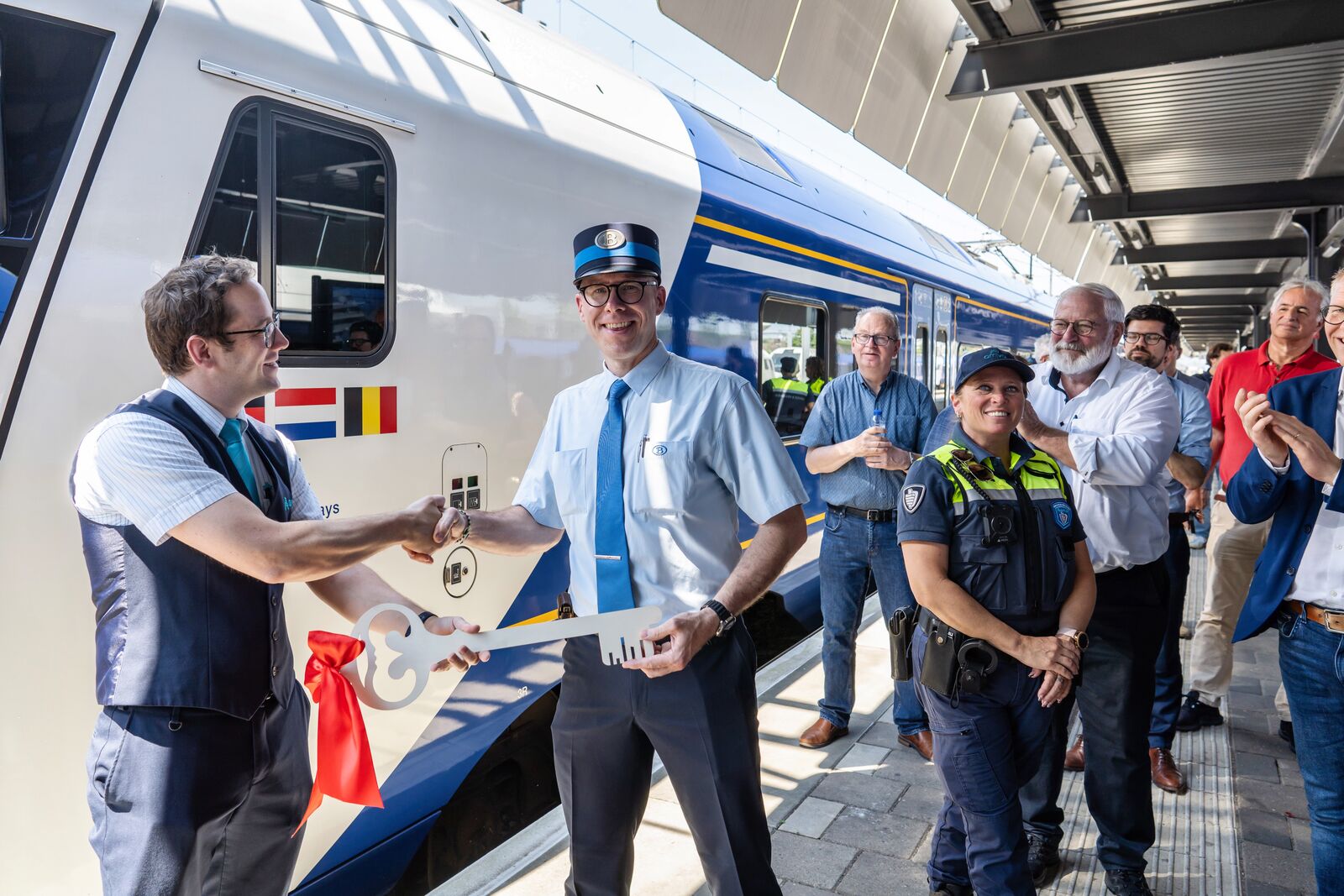 Voor een blauwwitte Arriva Drielandentrein zien we een ceremoniële sleuteloverdracht om de start van de nieuwe treindienst te markeren. 