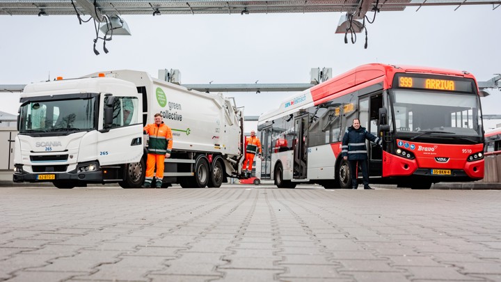 Links een witte elektrische vuilniswagen met bestuurder en rechts een rode elektrische Arriva-bus met chauffeur onder laadinfra. 