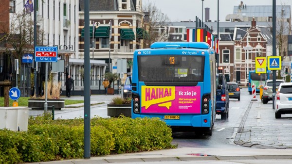 Een Arriva-bus in een stedelijke omgeving met een roze advertentie op de achterkant die zegt: "Hai Hai, Ik zie je."